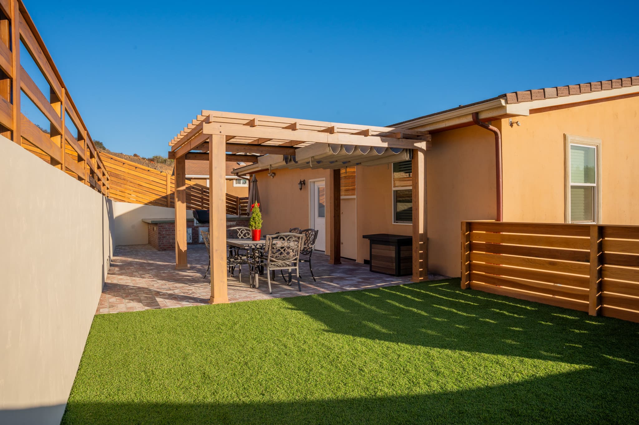 A beautifully designed backyard in San Diego featuring tiered retaining walls, artificial turf, custom wooden fencing, and outdoor lighting.