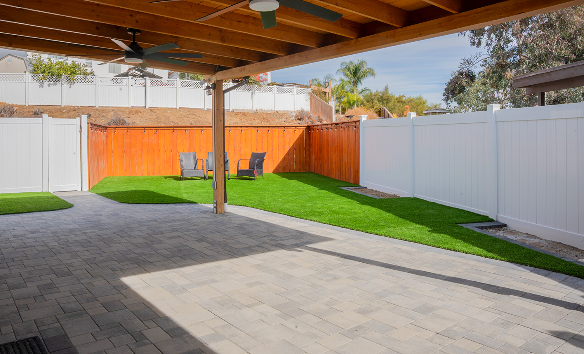 Pavers under pergola with artificial turf backyard in San Diego